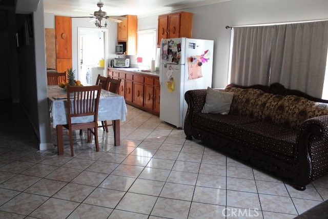 kitchen featuring ceiling fan, light tile patterned floors, white refrigerator, and crown molding