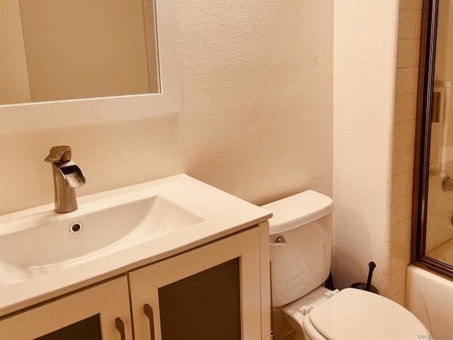 full bathroom featuring combined bath / shower with glass door, vanity, and toilet