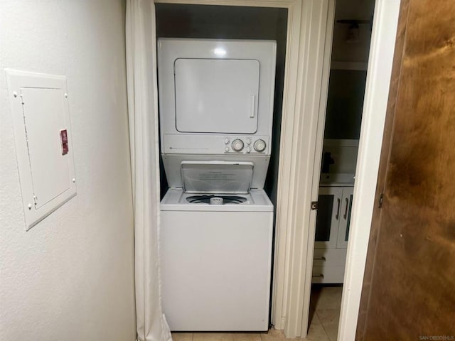 washroom featuring light tile patterned floors, stacked washer and clothes dryer, and electric panel