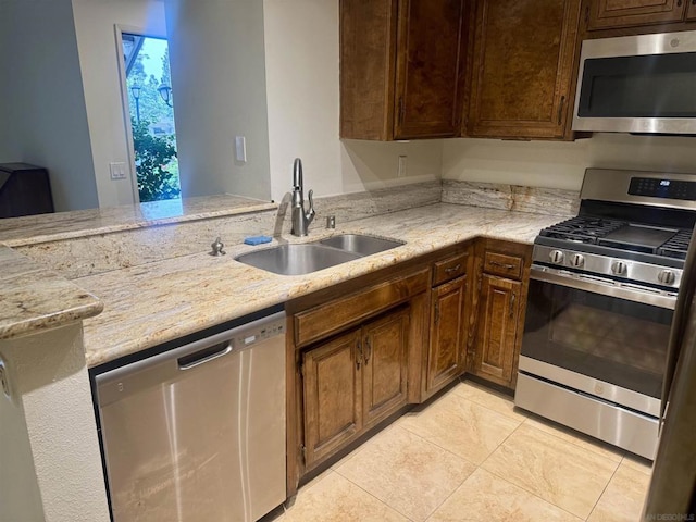 kitchen featuring kitchen peninsula, stainless steel appliances, light tile patterned flooring, light stone countertops, and sink