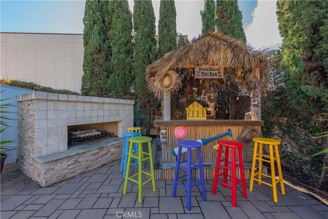 view of playground featuring an outdoor stone fireplace, a patio, and an outdoor bar