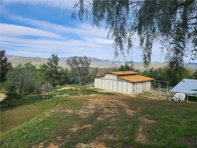 view of yard with an outbuilding, a rural view, and a mountain view