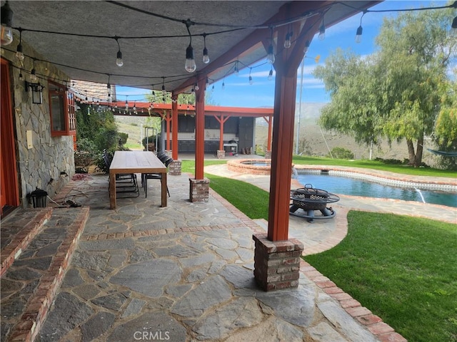 view of patio featuring a swimming pool with hot tub and an outdoor fire pit