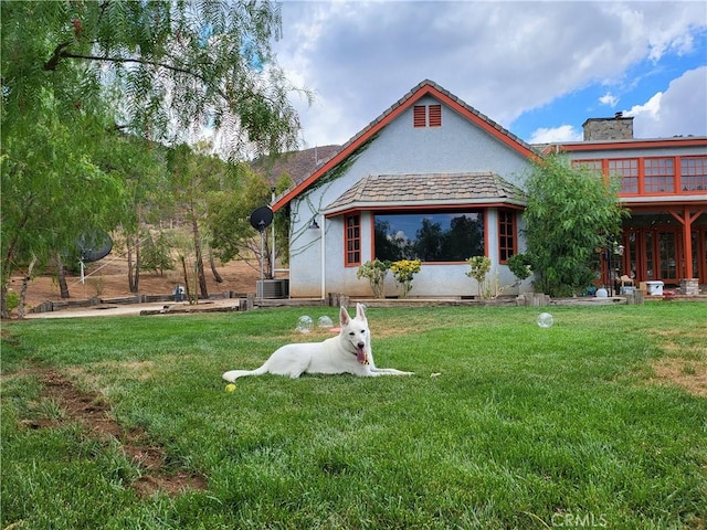 rear view of house featuring a lawn, central AC unit, and a wooden deck