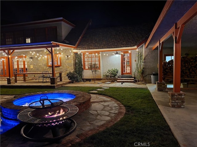 back house at twilight featuring a patio and a fire pit