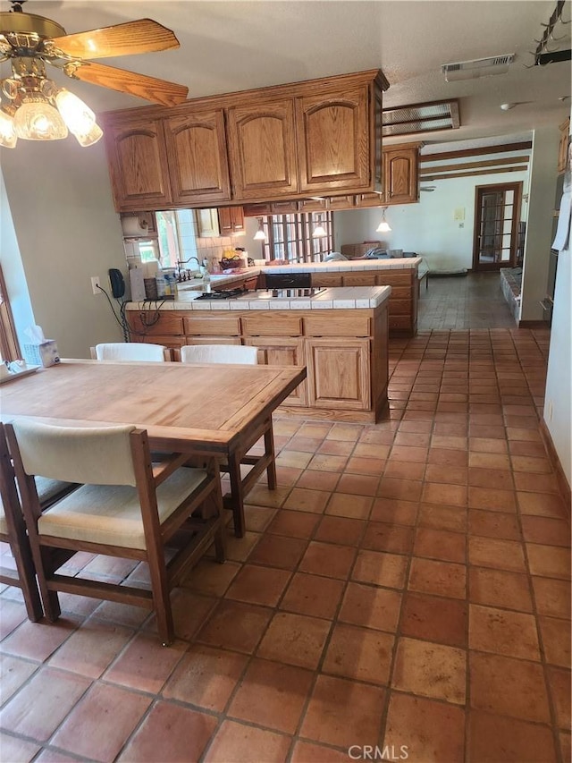 kitchen with ceiling fan, tile patterned floors, and tile countertops