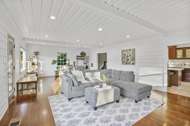 living room with wood-type flooring, wood walls, and beamed ceiling