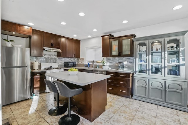 kitchen with stainless steel fridge, a center island, light tile patterned flooring, dark brown cabinets, and sink