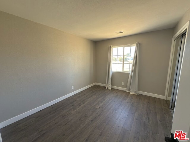 unfurnished room with dark wood-type flooring