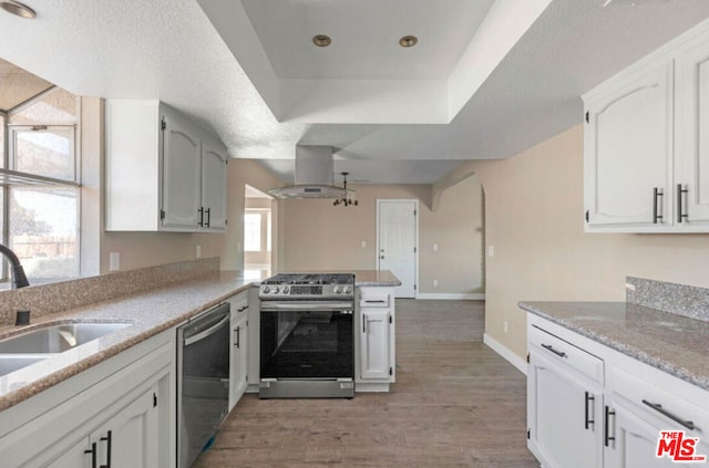 kitchen featuring white cabinets, kitchen peninsula, island range hood, and stainless steel appliances