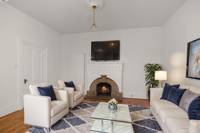 living room with hardwood / wood-style flooring and a brick fireplace