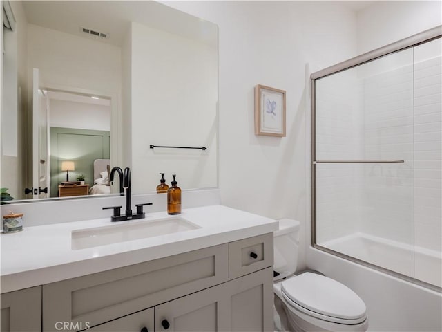 full bathroom featuring vanity, combined bath / shower with glass door, and toilet