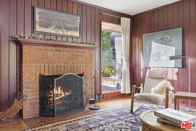 sitting room featuring hardwood / wood-style floors, wooden walls, and a fireplace