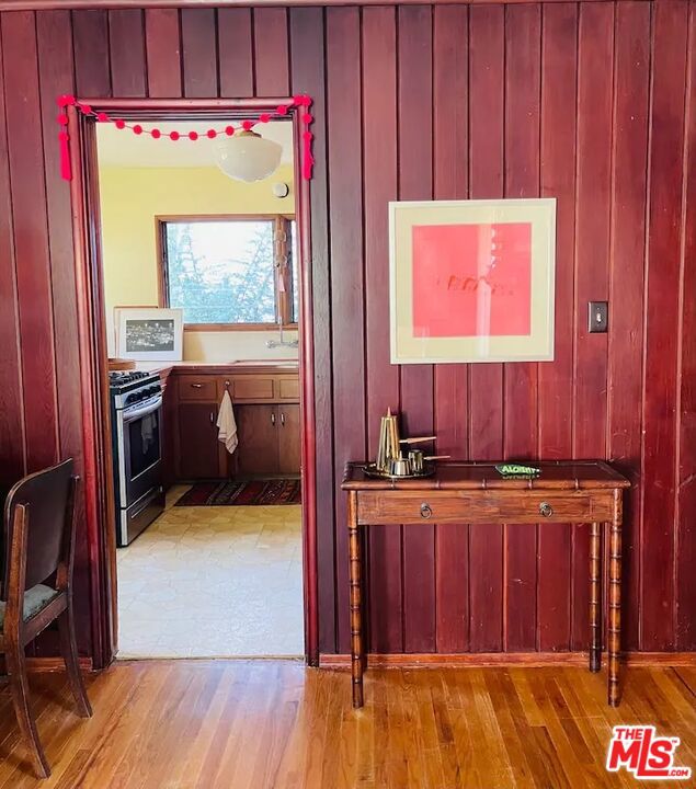 corridor with sink, wood walls, and light hardwood / wood-style flooring