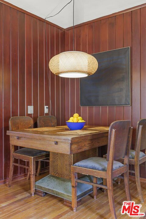 dining area featuring light wood-type flooring and wood walls