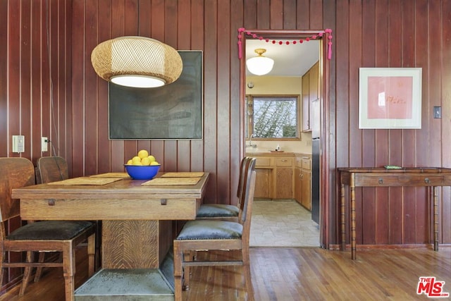 dining area featuring wood walls and light hardwood / wood-style flooring