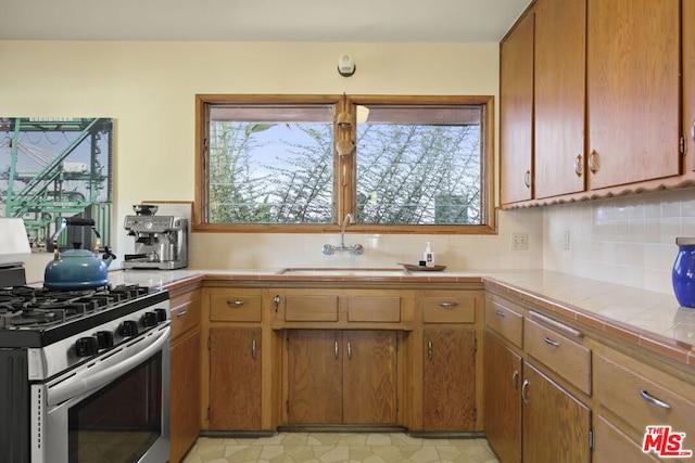 kitchen featuring a wealth of natural light, tile countertops, gas range, and sink