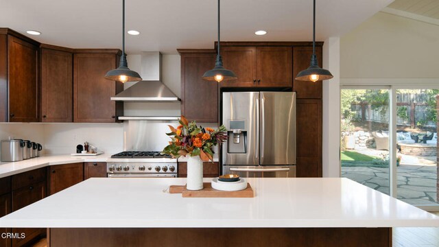 kitchen featuring wall chimney exhaust hood, a center island, decorative light fixtures, and appliances with stainless steel finishes