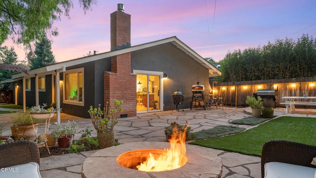 back house at dusk with a fire pit and a patio area