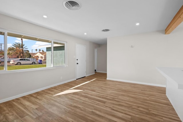 unfurnished room with beam ceiling and hardwood / wood-style floors