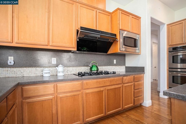 kitchen with decorative backsplash, appliances with stainless steel finishes, and light hardwood / wood-style flooring