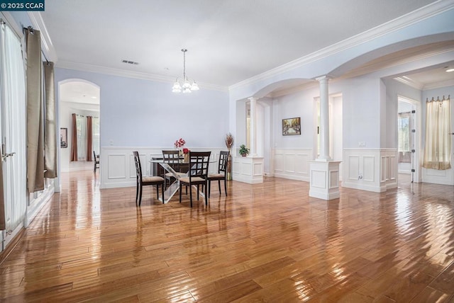 dining area with plenty of natural light, crown molding, a chandelier, and decorative columns