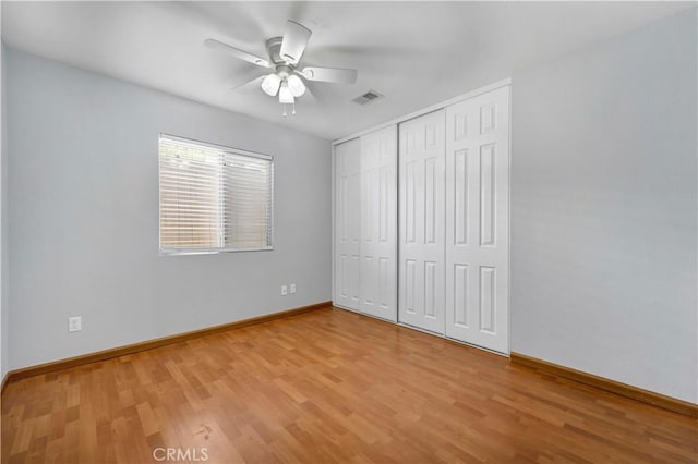 unfurnished bedroom with ceiling fan, wood-type flooring, and a closet