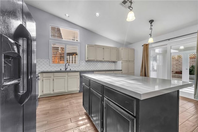 kitchen featuring a center island, lofted ceiling, decorative light fixtures, backsplash, and black fridge with ice dispenser