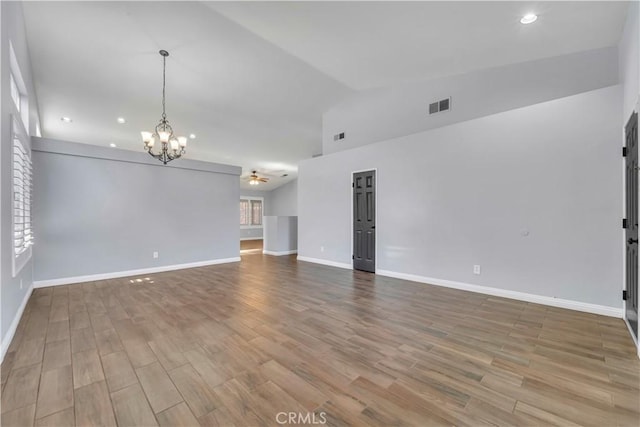 unfurnished living room featuring vaulted ceiling, ceiling fan with notable chandelier, and hardwood / wood-style flooring