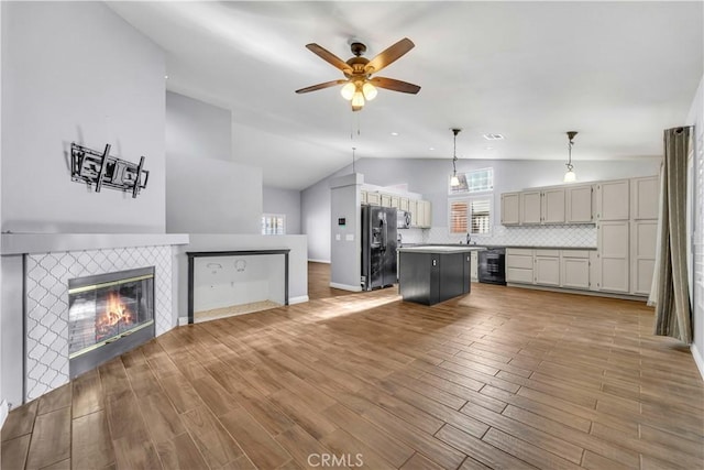 kitchen featuring black fridge, a center island, decorative backsplash, hanging light fixtures, and beverage cooler