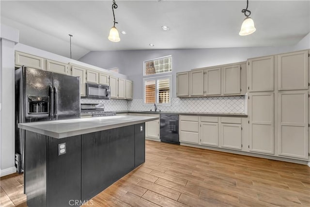 kitchen featuring decorative backsplash, hanging light fixtures, vaulted ceiling, a kitchen island, and black appliances