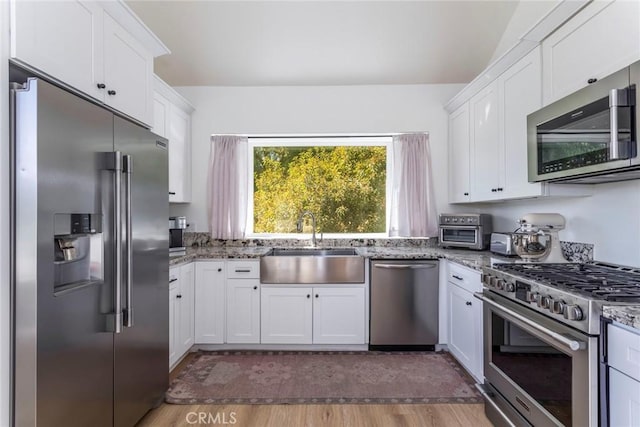 kitchen with high end appliances, light stone counters, and white cabinets