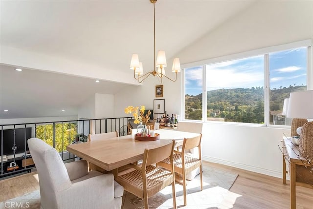 dining area featuring an inviting chandelier, lofted ceiling, and light wood-type flooring