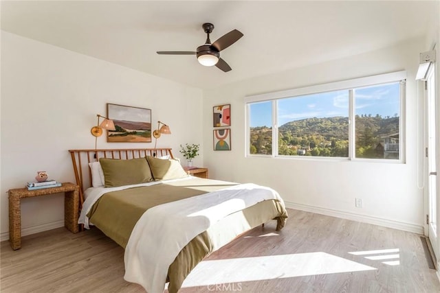 bedroom featuring a mountain view, light hardwood / wood-style flooring, and ceiling fan