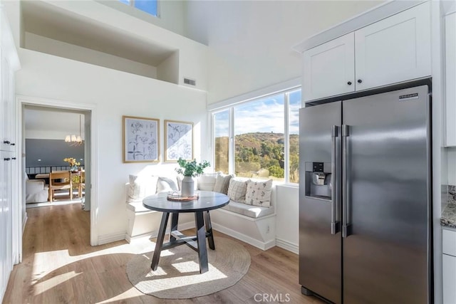 kitchen with breakfast area, high quality fridge, white cabinetry, and light wood-type flooring