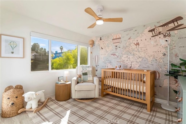 bedroom featuring a nursery area and ceiling fan