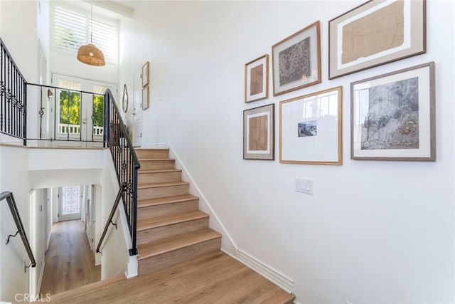 stairs with a towering ceiling and hardwood / wood-style floors