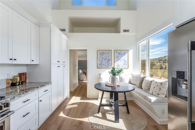 kitchen featuring light stone counters, appliances with stainless steel finishes, light hardwood / wood-style flooring, and white cabinets