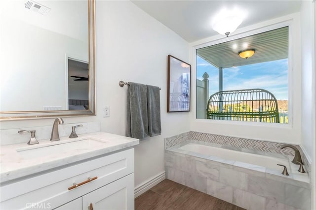 bathroom featuring vanity, hardwood / wood-style floors, and tiled tub