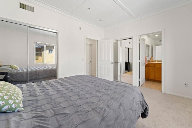 bedroom with ensuite bath, light carpet, a closet, and ornamental molding