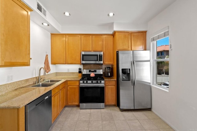 kitchen featuring light stone countertops, sink, appliances with stainless steel finishes, and light tile patterned floors