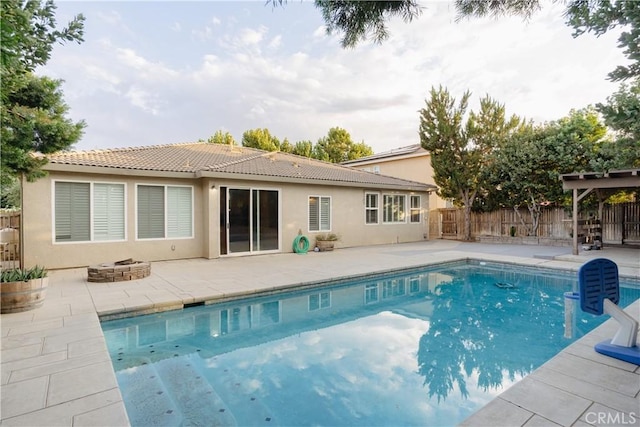 back of house featuring a fenced in pool, a fire pit, and a patio area