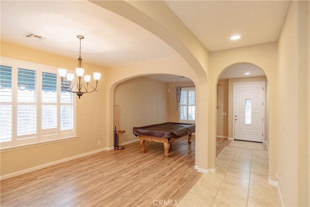 foyer entrance with pool table, light hardwood / wood-style floors, and a chandelier