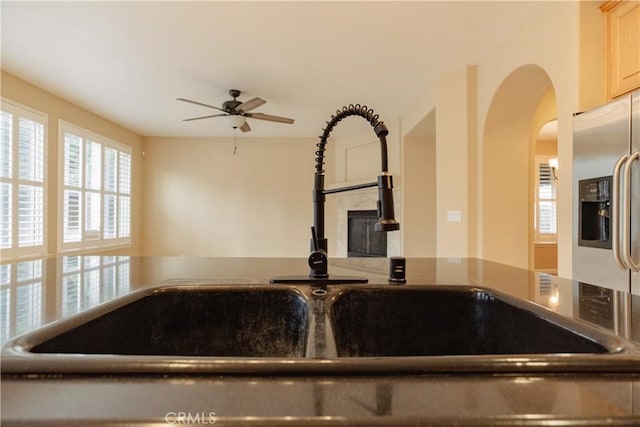 room details featuring ceiling fan, light brown cabinetry, stainless steel fridge with ice dispenser, and sink