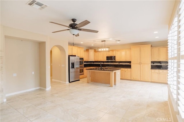 kitchen featuring light brown cabinetry, tasteful backsplash, plenty of natural light, an island with sink, and stainless steel appliances