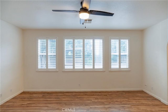 spare room featuring ceiling fan, light hardwood / wood-style floors, and a wealth of natural light