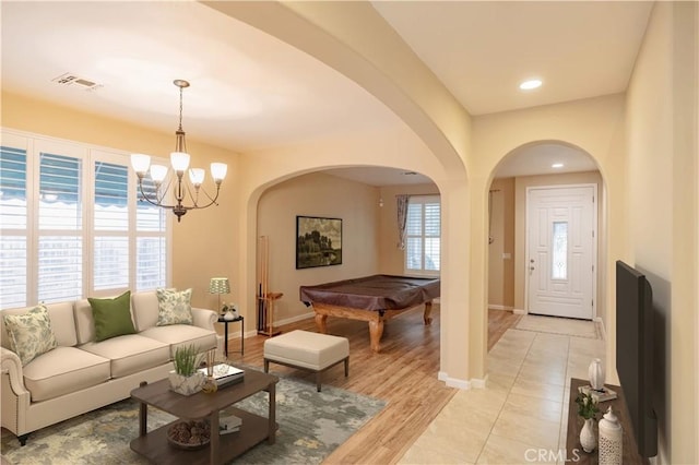 living room with an inviting chandelier, light hardwood / wood-style flooring, and billiards