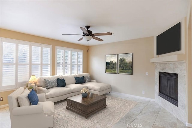 living room featuring a tiled fireplace, light tile patterned floors, and ceiling fan