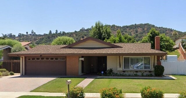 ranch-style house featuring a front yard, a garage, and a mountain view