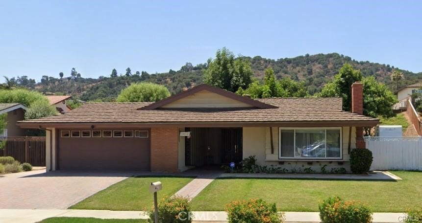 ranch-style house featuring a garage, a front lawn, and a mountain view